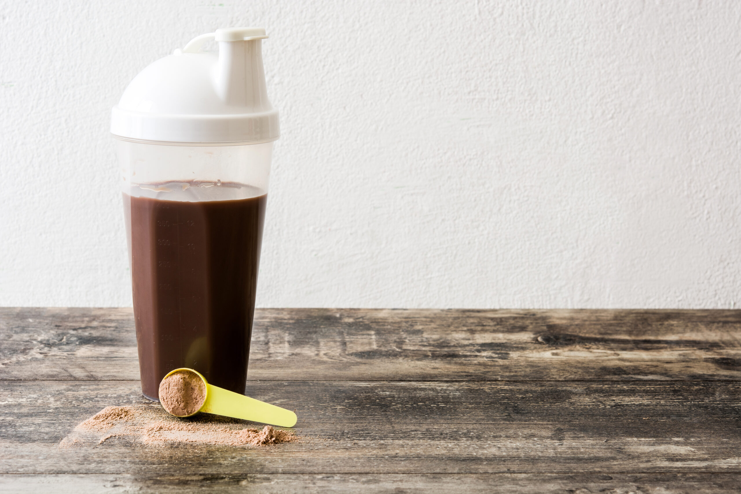 Chocolate protein shake on wooden table. Copyspace