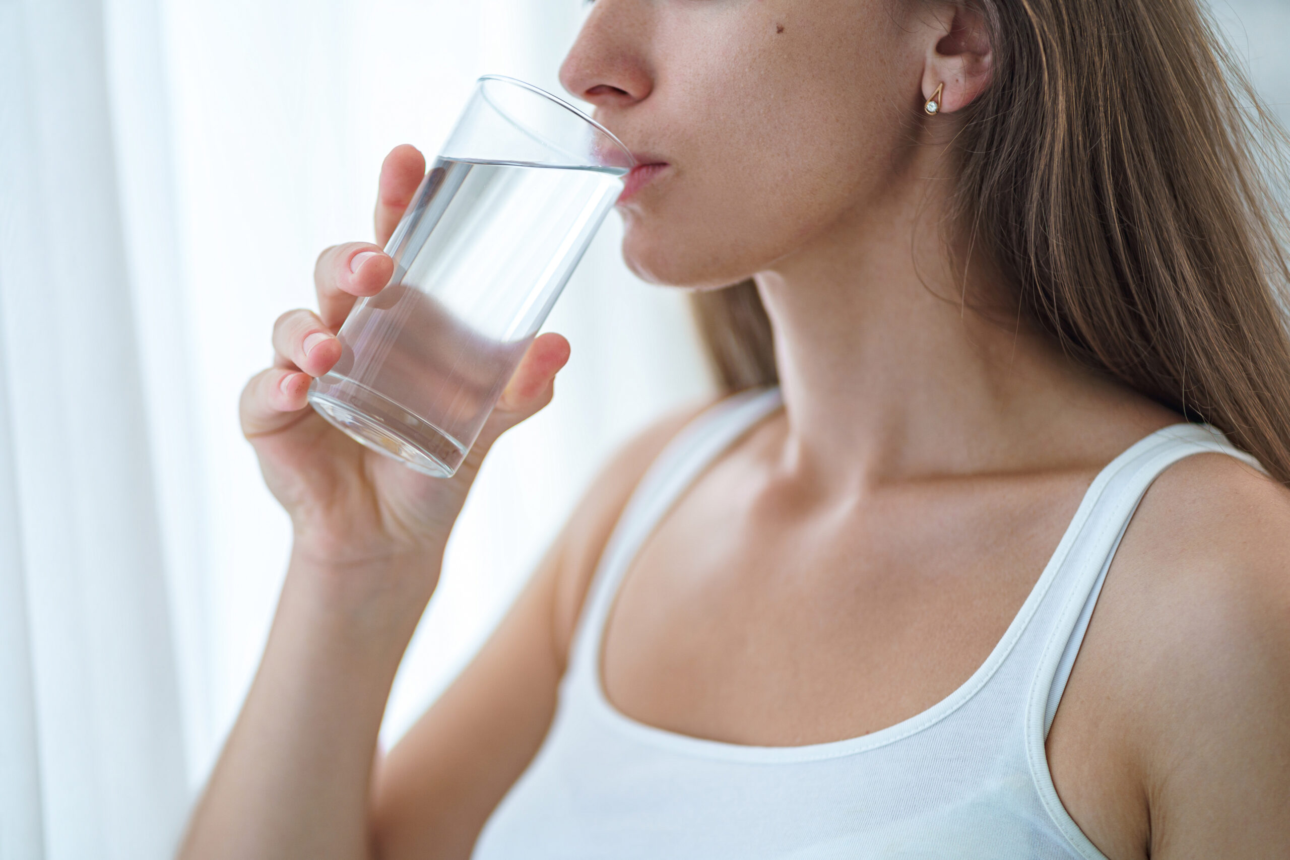 Drinking woman drinks clean purified glass of water in the morni