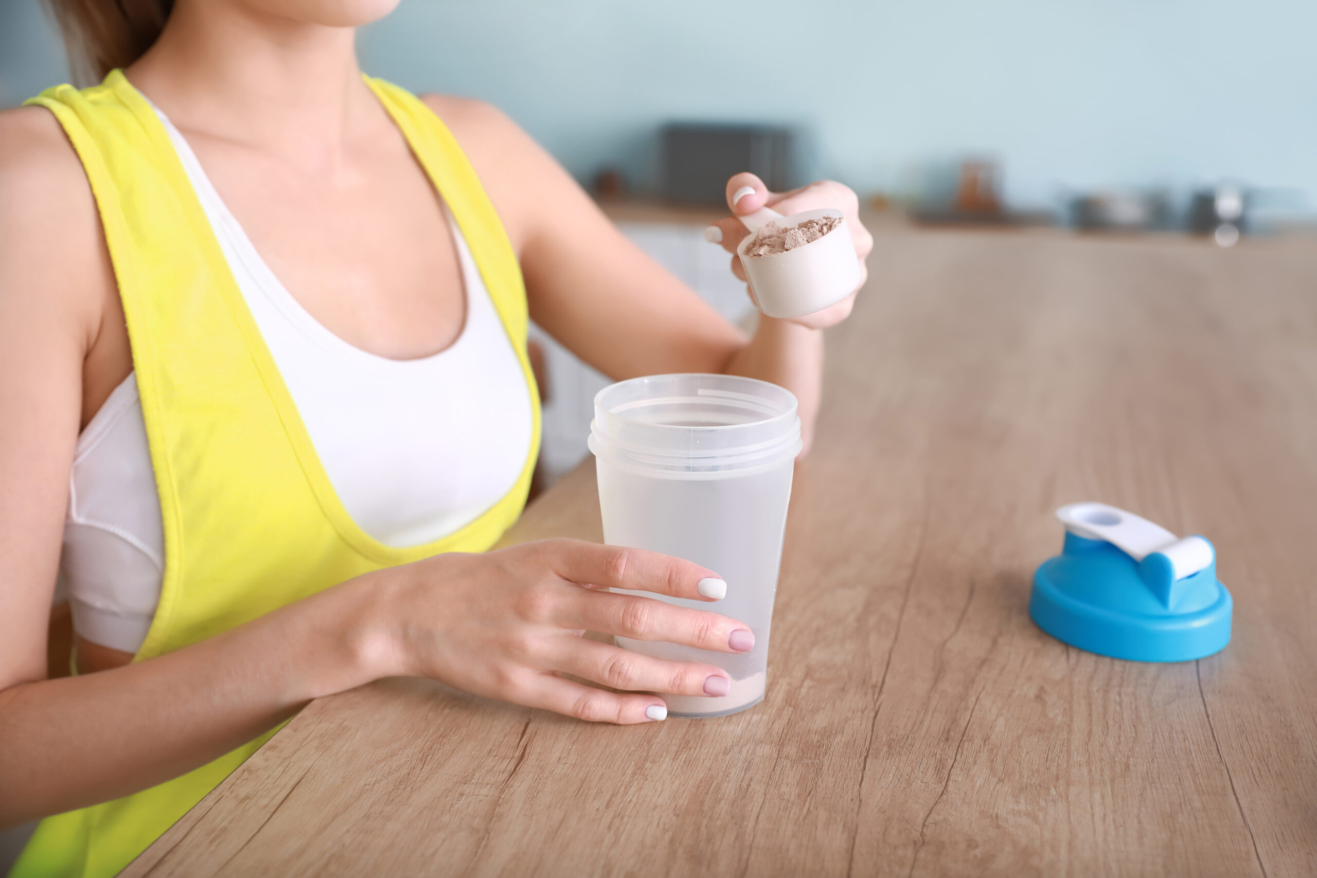 Sporty young woman making protein shake at home