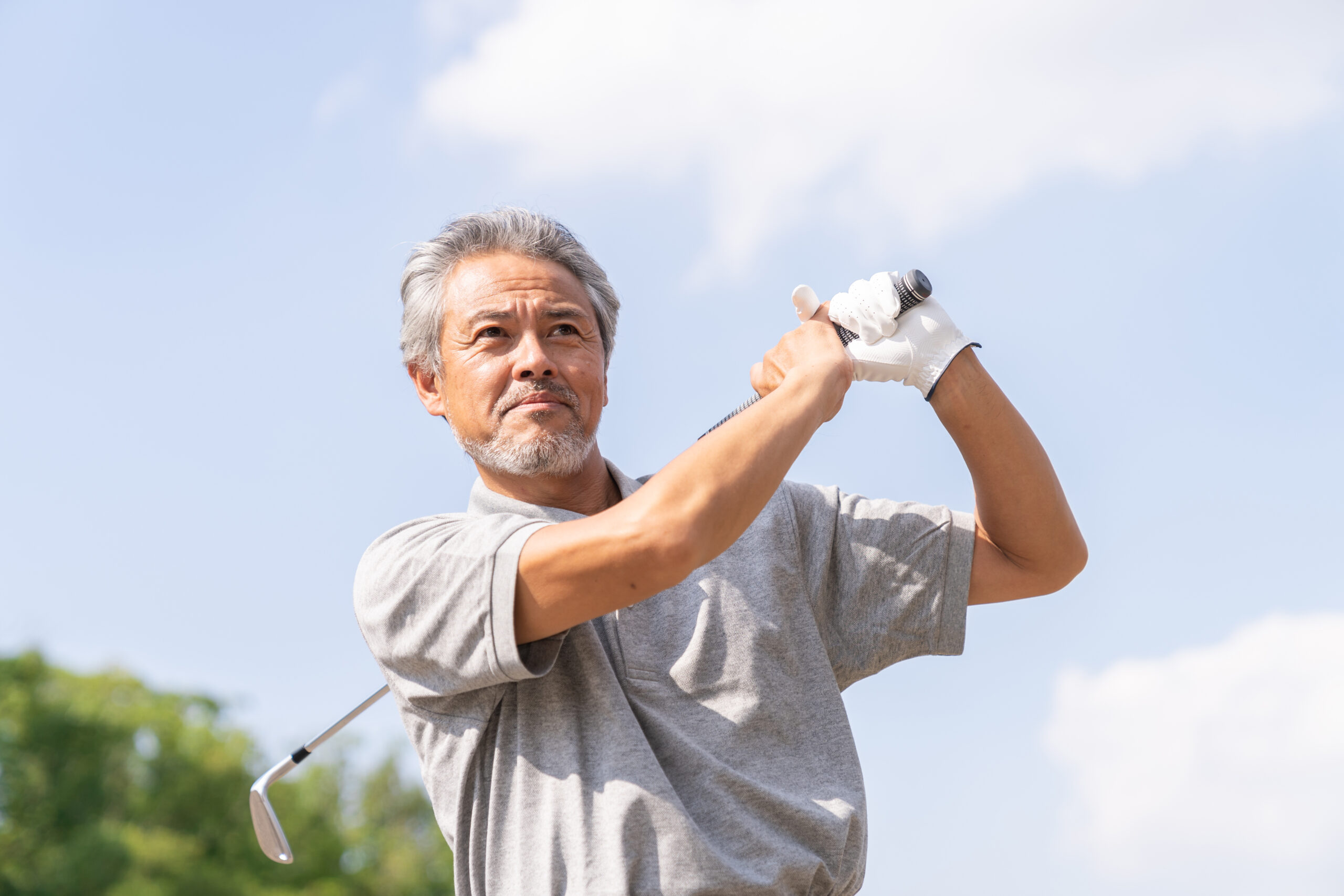 ゴルフをするシニア男性
