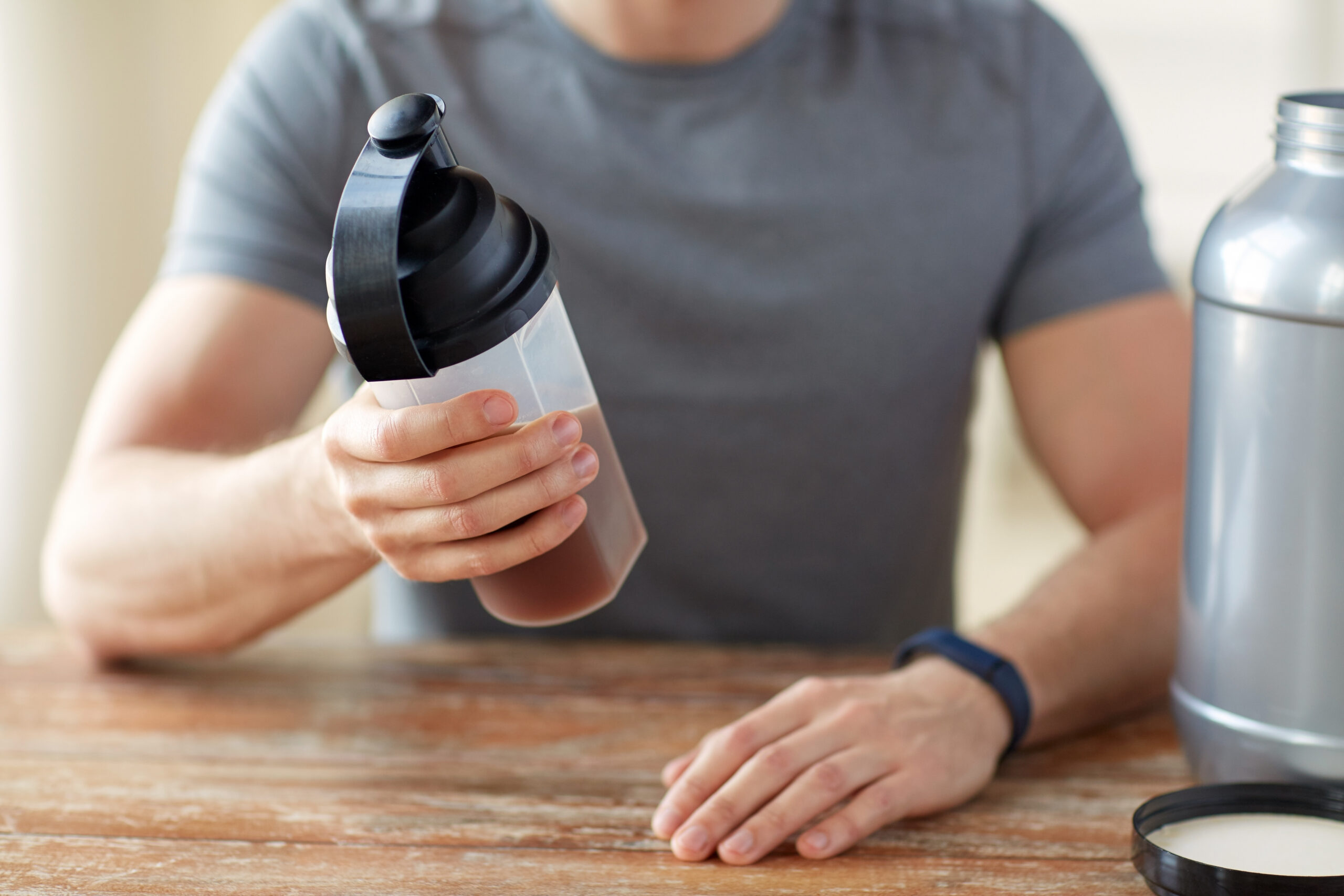 close up of man with protein shake bottle and jar