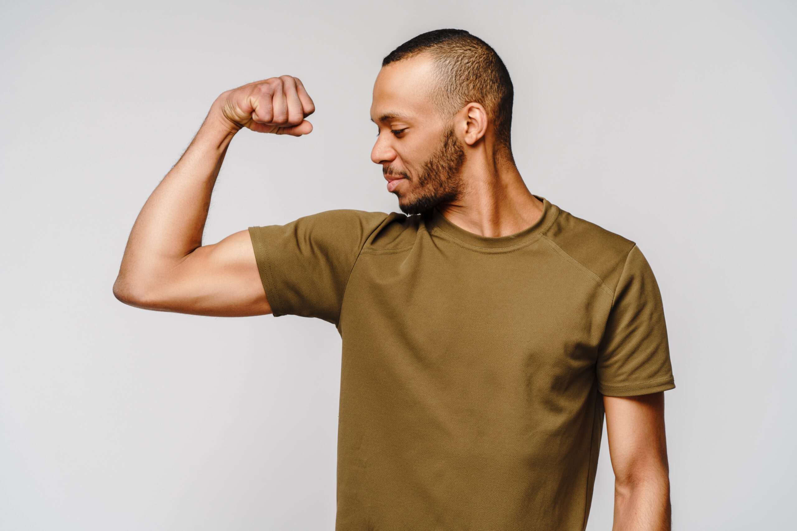 Close up portrait of a happy african american man wearing t-shirt flexing bicep arm muscle