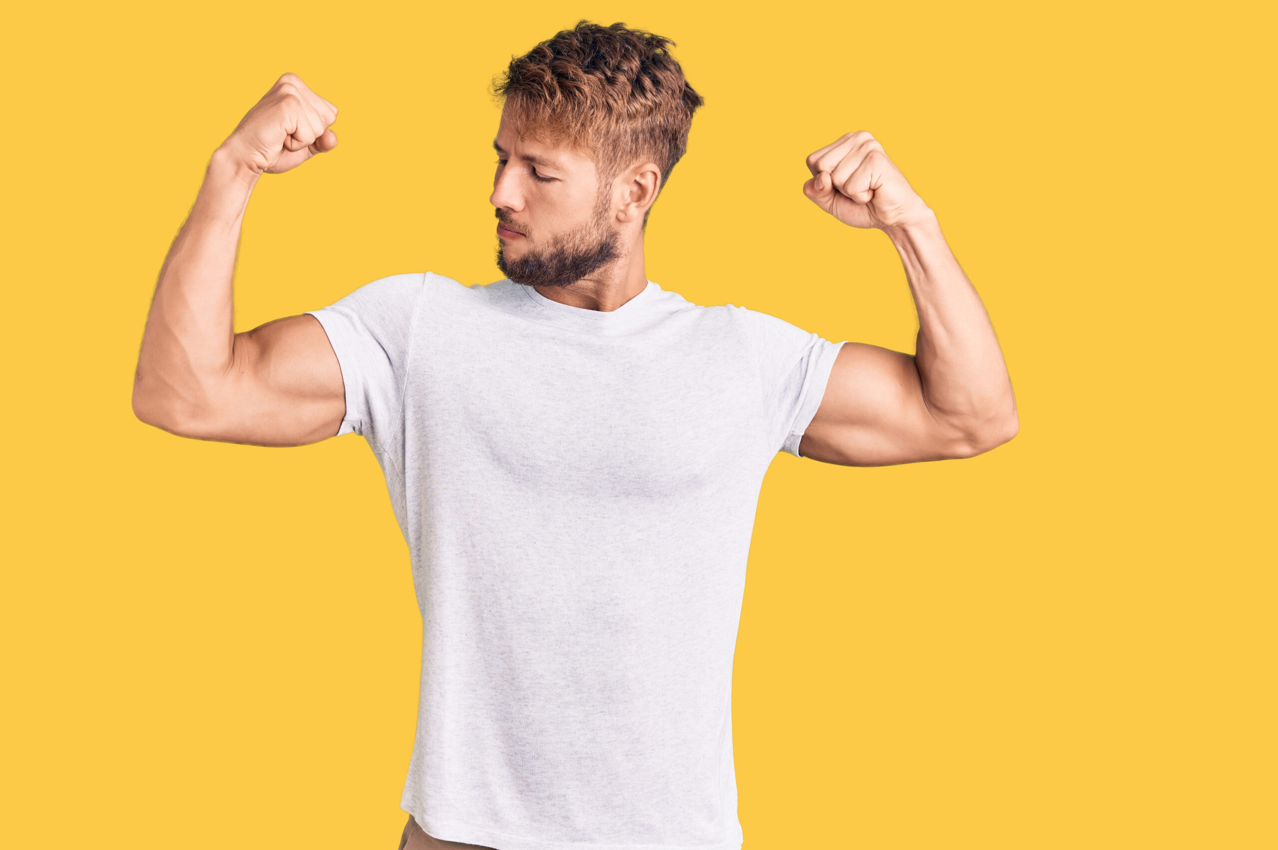 Young caucasian man wearing casual white tshirt showing arms muscles smiling proud. fitness concept.