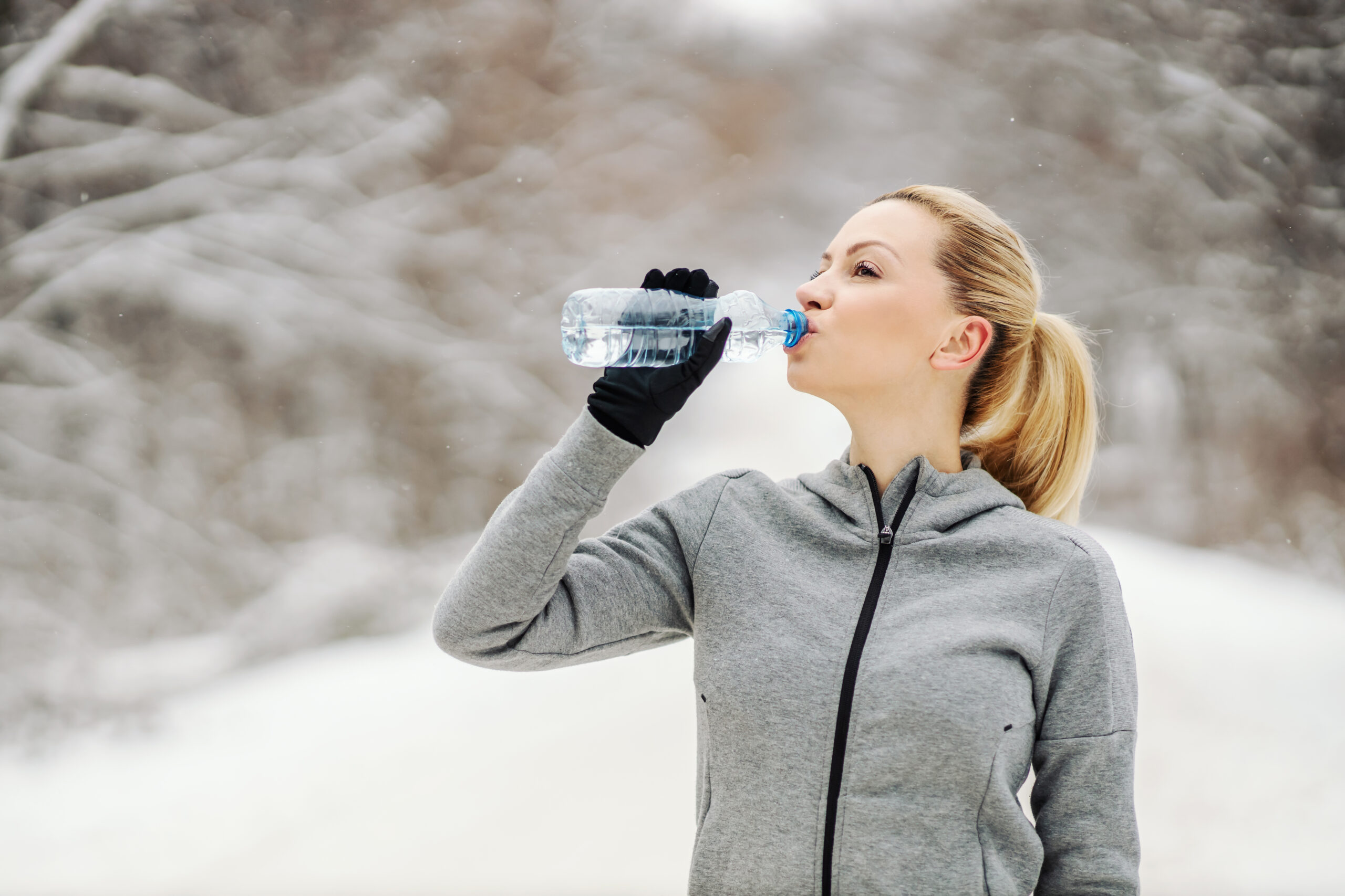 Sportswoman drinking water and taking a break from exercising wh