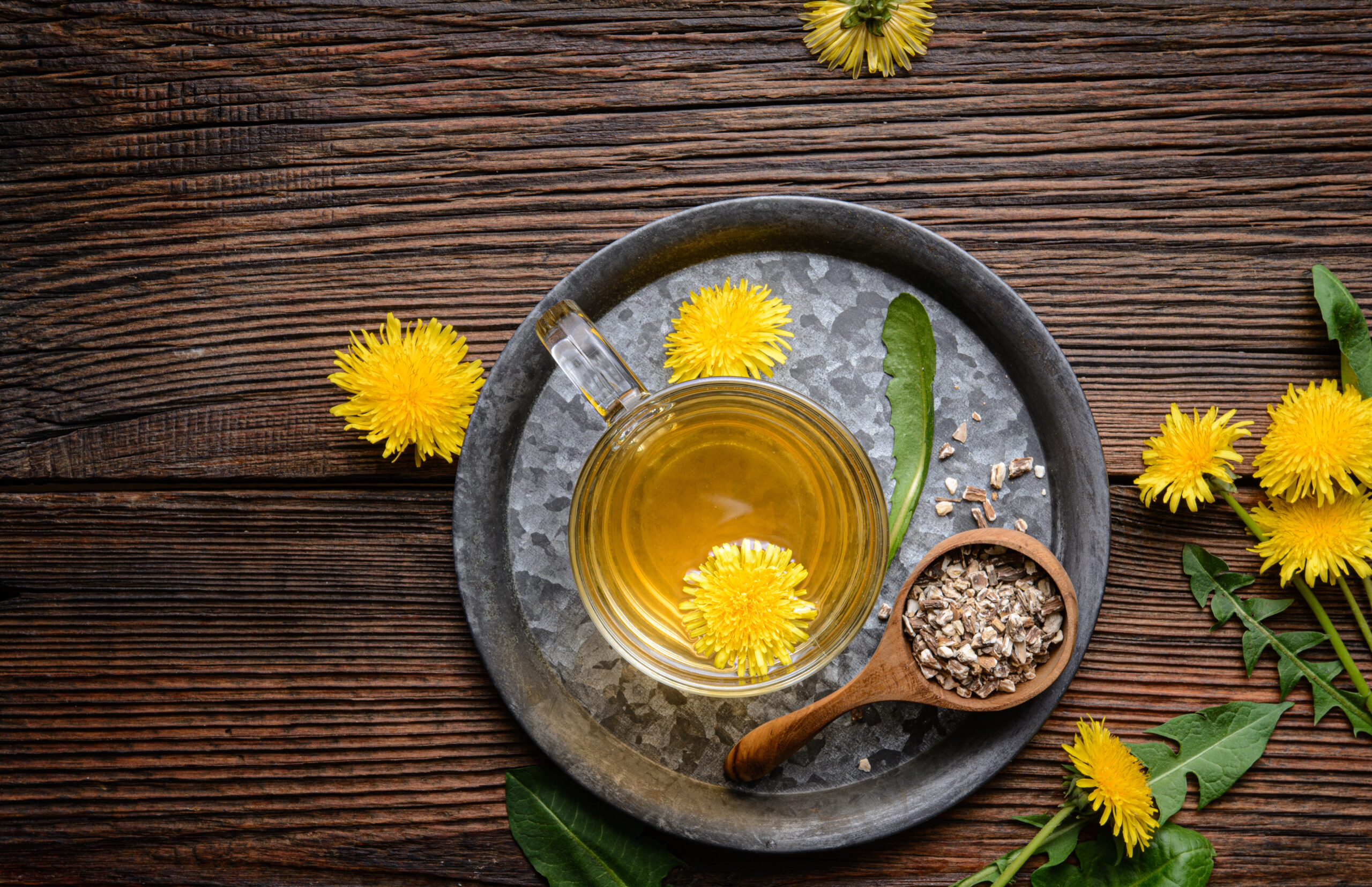 Herbal drink for liver detox, dandelion root tea in a glass cup decorated with fresh flowers with copy space